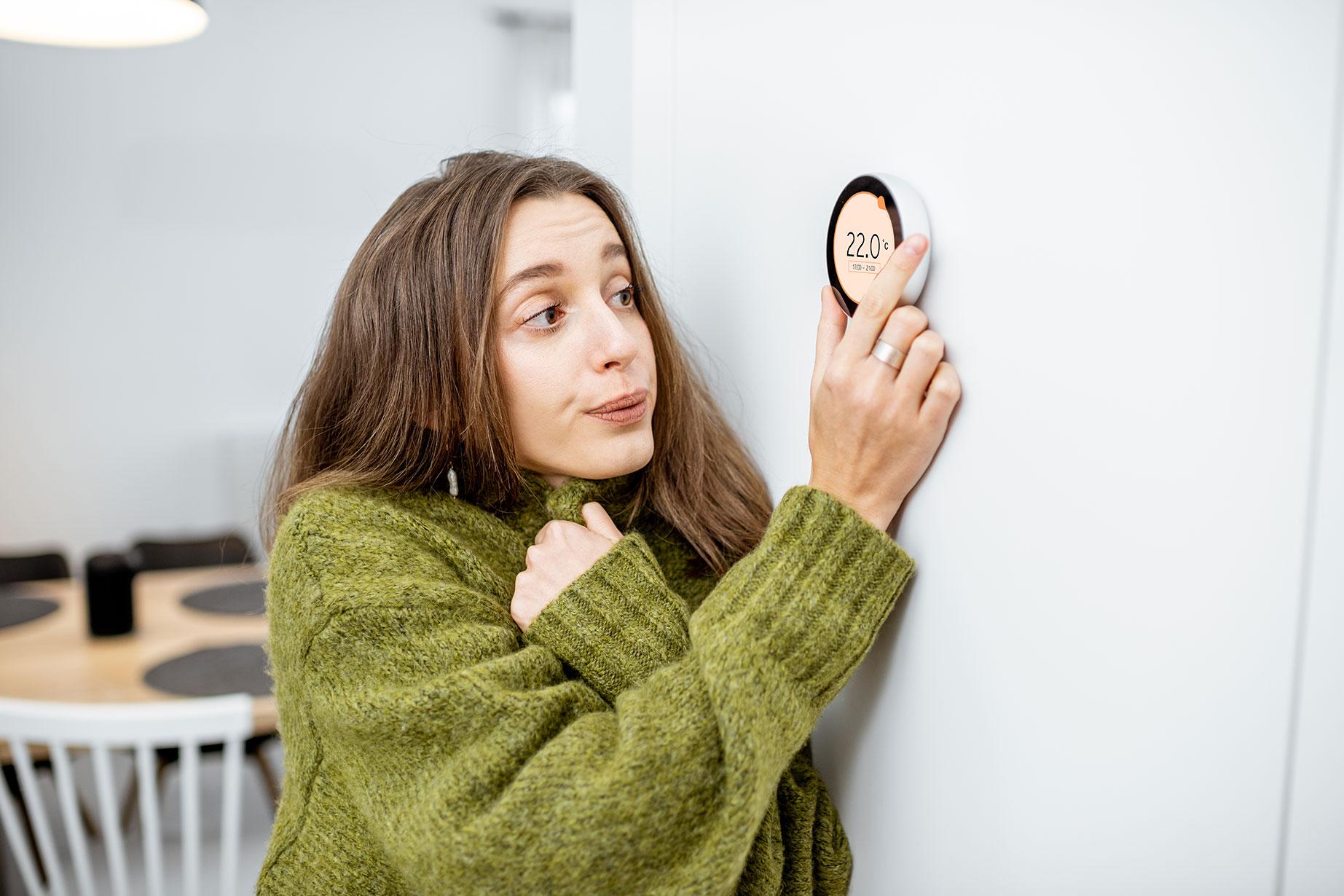 cold woman turning up the furnace